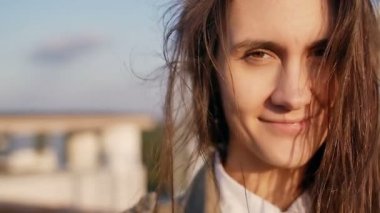 wind amazing blowing long hair girl. happy smiling woman standing on the roof at the sunset, looking at camera. slow mo
