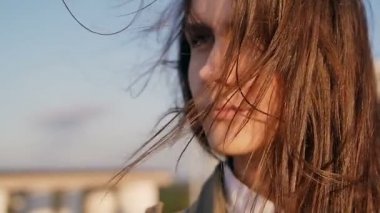 gün batımında çatıda duran düşünceli genç güzel kadın, onu uzun koyu saçları rüzgar esen. yavaş çekim.