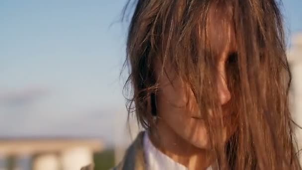 Concerned thoughtful young beautiful woman standing on the roof at the sunset, her long hair blowing wind. slow motion. — Stock Video