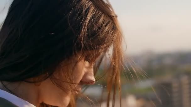 Wind blows long dark hair. girl standing on the roof with his head down. close up. Slow motion — 图库视频影像