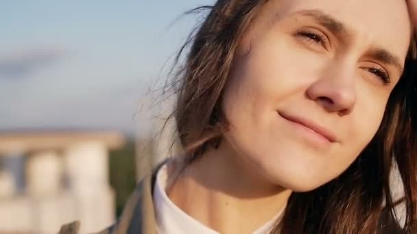 Feliz sonriente joven hermosa mujer de pie en el techo al atardecer, su largo cabello oscuro soplando viento. cámara lenta . — Vídeo de stock