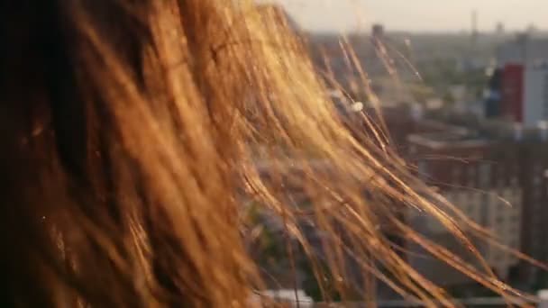 Vista posteriore. primo piano Vento soffia lunghi capelli scuri belle giovani donne. ragazza in piedi sul tetto al tramonto. Lento mo — Video Stock