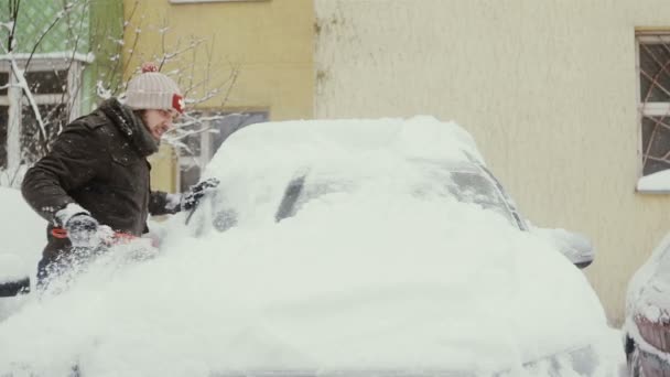 Mann räumt im Winter Schnee von seinem Auto auf der Straße, — Stockvideo