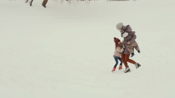 Joven madre con sus hijos jugando y divirtiéndose en la nieve — Vídeos de Stock