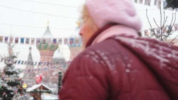 Woman talking on the phone standing in the winter on the Red Square in Moscow, in front of St. Basil Cathedral — Stok video