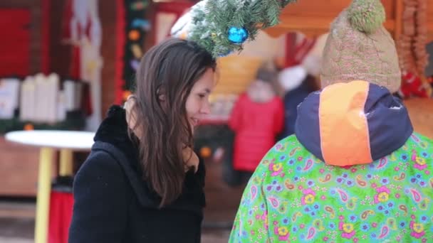 러시아 모스크바에서 열린 크리스마스 박람회에서 판매자와 이야기하는 아름다운 젊은 여성. — 비디오