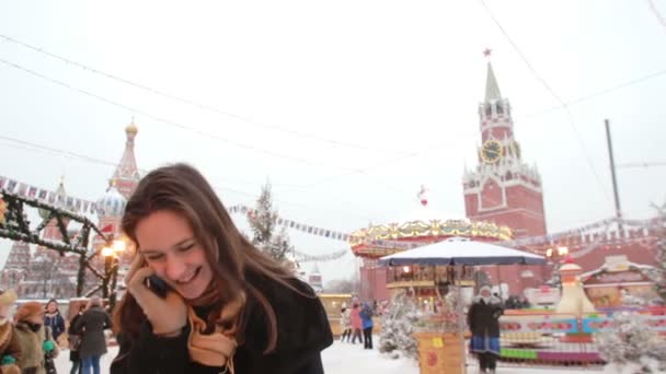 Woman talking on phone standing in the winter on the Red Square in Moscow, in front of Kremlin and St. Basils Cathedral — Stock Video