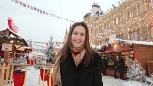 Uśmiechnięta dziewczyna wysyła pocałunki stojące w zimie na placu Czerwonym w Moskwie, przed State Department Store gum — Wideo stockowe