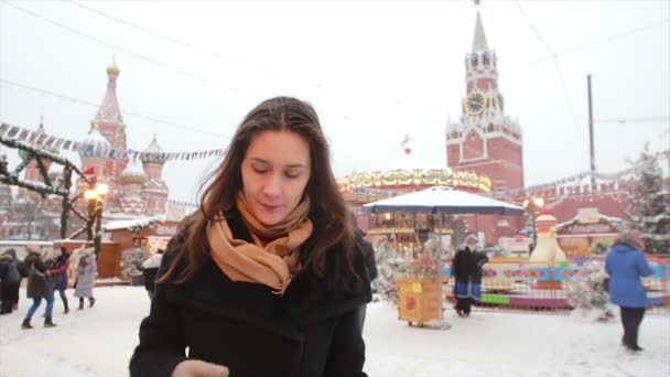 O femeie care folosea smartphone-ul stând iarna în Piața Roșie din Moscova, în fața Kremlinului și a Catedralei Sf. Vasile — Videoclip de stoc