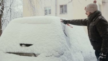 adam kışın sokakta arabasından kar temizler, geri görünümü,