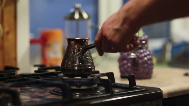 Handen van een man zetten een koffiepot op een fornuis, het instellen van vuur. — Stockvideo