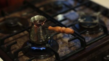 Ateşe hazırlanan bir kahve demliğinde kahve manzarası. Sonunda bir kaşıkla karıştıran bir adamın elleri.