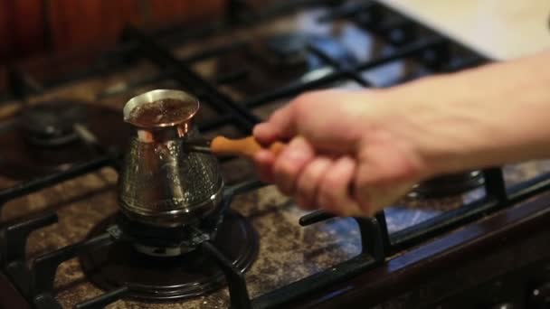 Ο καφές βράζει σε μια κανάτα καφέ. Τα χέρια ενός άντρα που παίρνει την κατσαρόλα και ρίχνει καφέ σε μια κούπα. — Αρχείο Βίντεο
