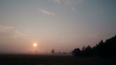 Gün doğumunda kırsal sahne sis ile yavaş yavaş çayır dan uzak alıyorum. Güneş yükselirken daha parlak parlar. Timelapse