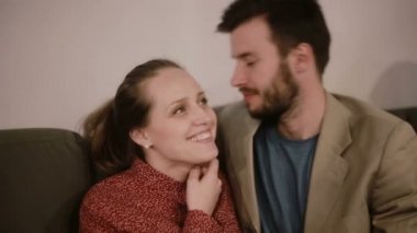 Bir adam ve bir kadın gülümsüyor ve konuşuyor. Bir adam kadın kulağına bir şeyler fısıldıyor..