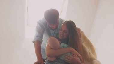 Yeni doğan oğlu onu bir sallanan sandalyede lulling gülümseyen anne. Baba 4 k olarak onun alnına öpücük