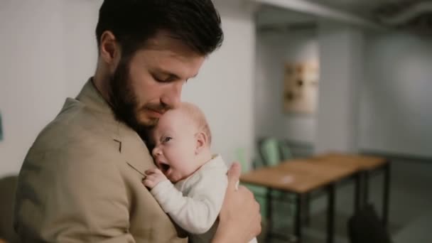 Młody mężczyzna trzyma dziecko na ramionach i rozmawia, całując go na policzku. Tło wyciągnięcia po profilach. — Wideo stockowe