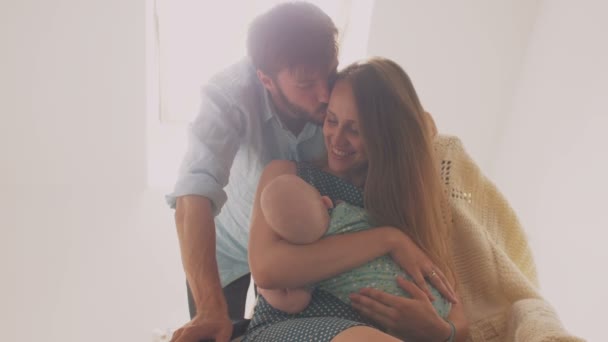 Lustiger Vater, der vor Freude von seinem neugeborenen Baby tanzt, fröhlich schöne, junge Mutter lächelnd im Schaukelstuhl sitzend. 4k — Stockvideo