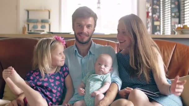 Familia de cuatro está sentado en el sofá y hablar. padre sosteniendo a su hijo recién nacido. 4k — Vídeos de Stock