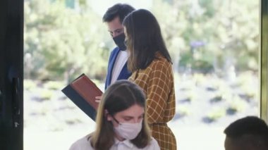 İki ciddi Kafkas iş adamı modern ofis boyunca Coronavirus yüz maskeleriyle çalışan belgelerle yürüyorlar..