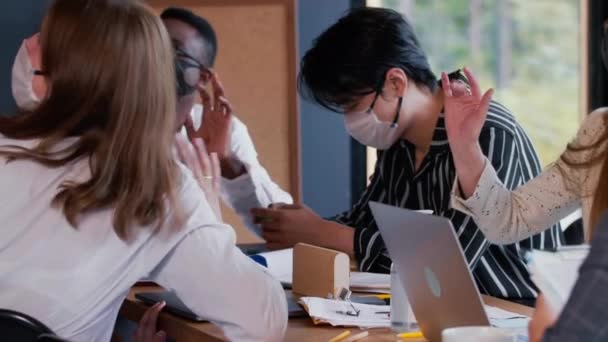 Masques visage comme nouveau mode de vie. Les jeunes gens d'affaires multiethniques heureux travaillent à la table de bureau moderne protégée de COVID-19 — Video