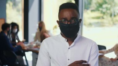 Halka açık yerlerde güvenlik önlemleri. Ofiste ağır çekimde yüz maskesi takan yakışıklı Afrikalı öğrenci portresi.