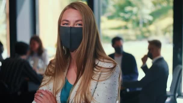 Veiligheidsmaatregelen op de werkplek. Portret van een mooie blanke ondernemer met masker op modern kantoor slow motion. — Stockvideo