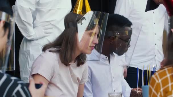 Кавказька молода жінка святкує день народження з багатонаціональними друзями в масках COVID-19 і пластикових щитах обличчя.. — стокове відео