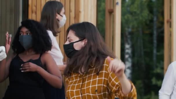 Kelompok senang teman-teman multietnis menari di luar ruangan pesta, semua dalam COVID-19 keselamatan pelindung topeng dan kostum — Stok Video
