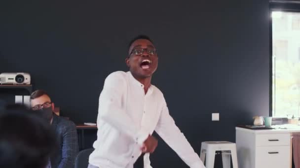 Feliz joven empresario africano se quita la máscara COVID-19, celebra la vida normal bajo confeti en la reunión del equipo de oficina. — Vídeos de Stock