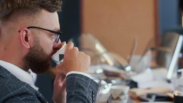 Yoğun modern ofiste iş akışı. Yakın plan mutlu, genç, sakallı, beyaz iş adamı takım masasında kahve içiyor.. — Stok video