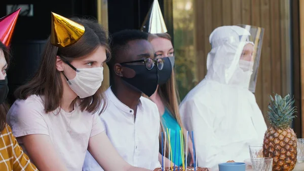 COVID-19 festa de aniversário celebração. Jovens amigos multiétnicos compartilham celebração vestindo máscaras e fantasias médicas — Fotografia de Stock