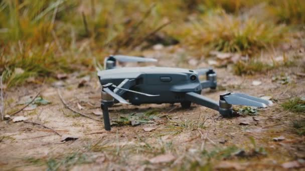 Nahaufnahme eines grauen modernen Drohnenflugzeugs, das am Boden liegt, dann einschaltet und abhebt, um Zeitlupe wegzufliegen. — Stockvideo