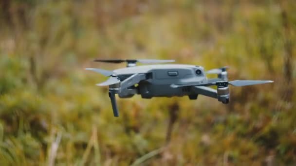 Close-up young casual Caucasian man is testing drone aircraft, hanging still in the air in the middle of autumn forest. — Stock Video