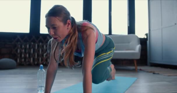 Närbild vacker sportig ung vit kvinna gör fitness träning hemma med smart klocka under självisolering. — Stockvideo