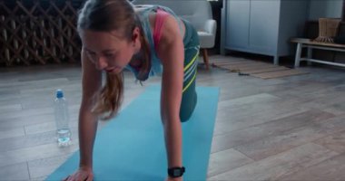 Güzel, kararlı, genç, beyaz bir kadın. Evde spor yapmaktan bıkmış. Kendini izole etme konusunda akıllı bir saat..