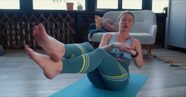 美しいスポーティな若い白人女性は、自己分離に健康を維持するためにスマートフォンで自宅でトレーニング演習を行う. — ストック動画