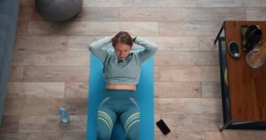 Manzaralı genç, güzel, beyaz bir kadın. Karantinada akıllı saatle evde antrenman yaptıktan sonra yoruldu..