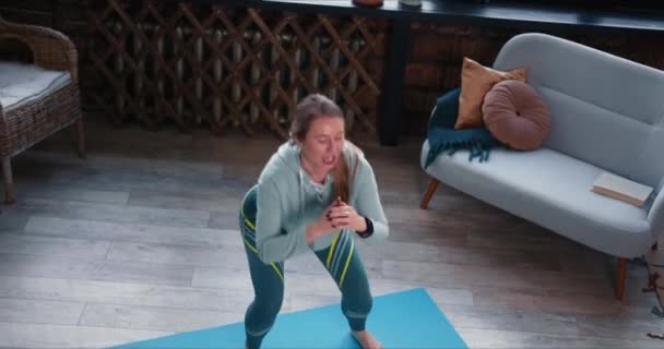 Zoom uit op jonge vrolijke blanke fitnesscoach vrouw leidt workout oefeningen online met laptop video conference call — Stockvideo