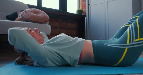 Side View zbliżenie młody sportowy atrakcyjna kobieta robi ćwiczenia brzucha w domu, aby zachować zdrowie na samoizolację. — Wideo stockowe