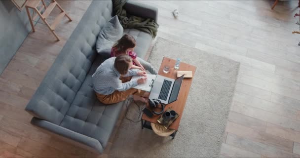 Visão superior jovem caucasiano mãe solteira está ajudando a estudar a filha adolescente em casa, verificando o papel usando laptop. — Vídeo de Stock