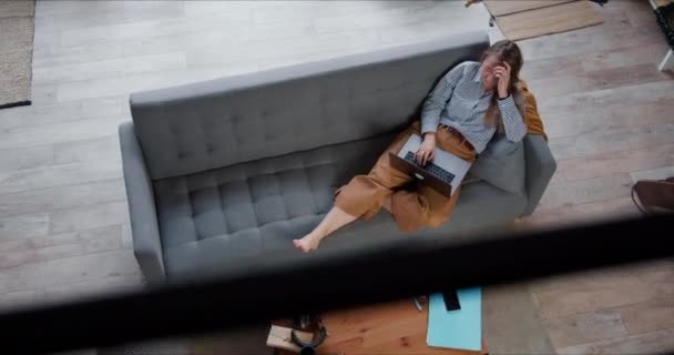 Ovanifrån vackra unga kaukasiska affärskvinna arbetar hemifrån på soffan med hjälp av laptop på själv isolering lockdown. — Stockvideo