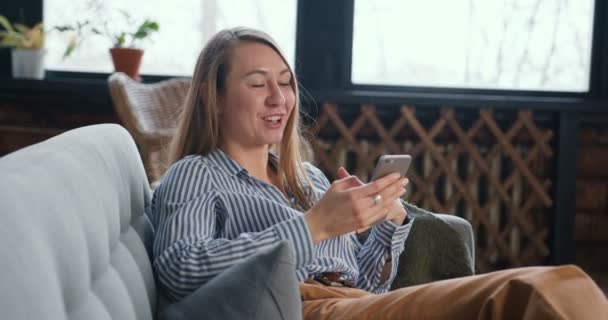 Hermosa mujer rubia joven hablando con un amigo de casa en auto aislamiento utilizando la aplicación de videollamada smartphone. — Vídeo de stock