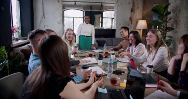 Ofis toplantısı masasında takım çalışması, çok ırklı meslektaşlar kendinden emin genç Afrikalı kadın patronla beyin fırtınası.