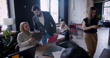 Başarılı genç erkek patron, modern çatı katında ağır çekimde çok ırklı iş arkadaşlarıyla iş birliği yapıyor.