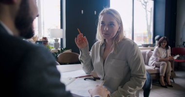 Güzel, kendine güvenen beyaz, sarışın bir kadın modern ofiste genç erkek HR ile iş görüşmesi yapıyor..