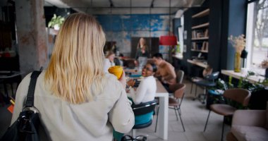 Kamera, kendinden emin sarışın kadın patronun çok ırklı ofis ekibi toplantısına kahve ile girmesini takip ediyor..