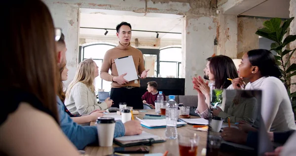 Feliz joven adulto asiático entrenador de negocios hombre dando un discurso para el equipo multiétnico en la oficina moderna lugar de trabajo cámara lenta. — Foto de Stock