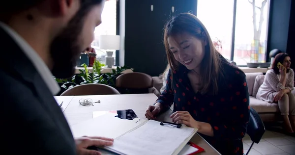 Young happy excited Asian woman taking job interview in modern multiethnic office, is greeted by male HR slow motion.