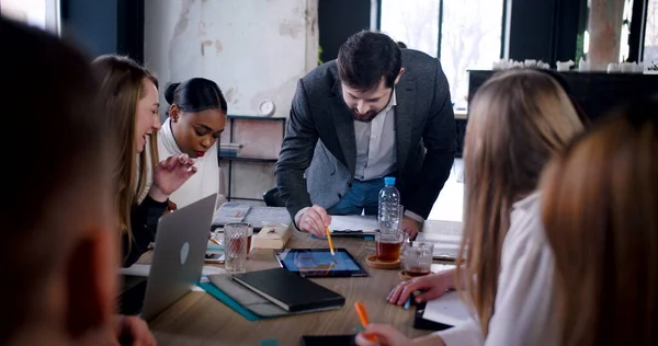 Concepto de trabajo en equipo. Joven jefe caucásico liderando la discusión en equipo multietnico en la oficina de moda usando tableta de cámara lenta. — Foto de Stock